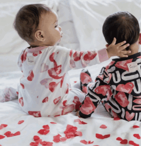 Two babies in heart-patterned pajamas celebrate Valentines Day.