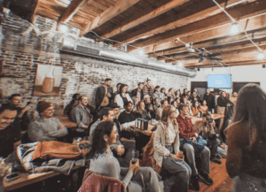 Engaged audience at an event, possibly a "Pitch-A-Friend" gathering.