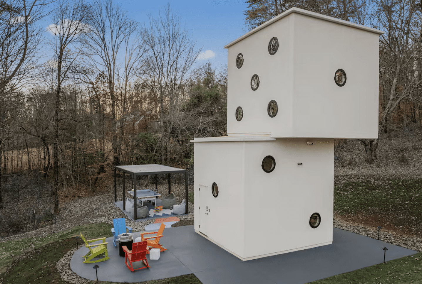 Unique dice-shaped tiny house with colorful outdoor seating and modern design.