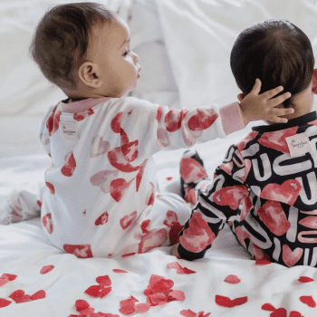 Two babies in heart-patterned pajamas celebrate Valentines Day.
